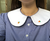 Collar of shirt. Navy gingham, white collar with navy piping, orange embroidery.